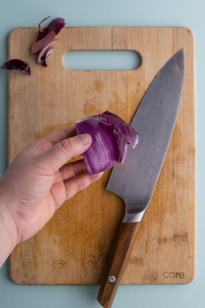 Peeling the outermost layer off of the onion to discard it