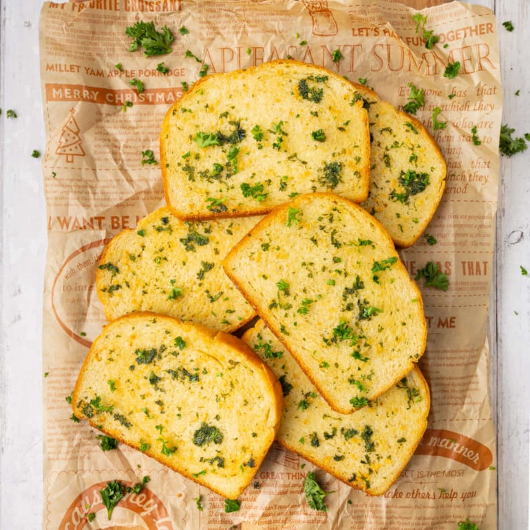 Six slices of Texas toast, piled on a piece of parchment paper.