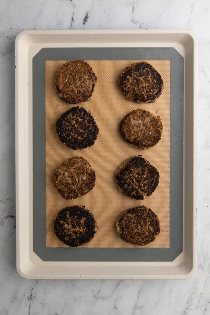 Lining patties up on a baking sheet to finish off in the oven