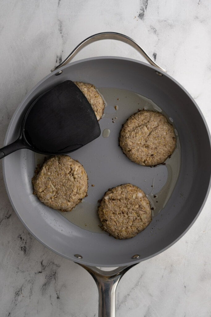 Using a spatula to flatten sausage patties