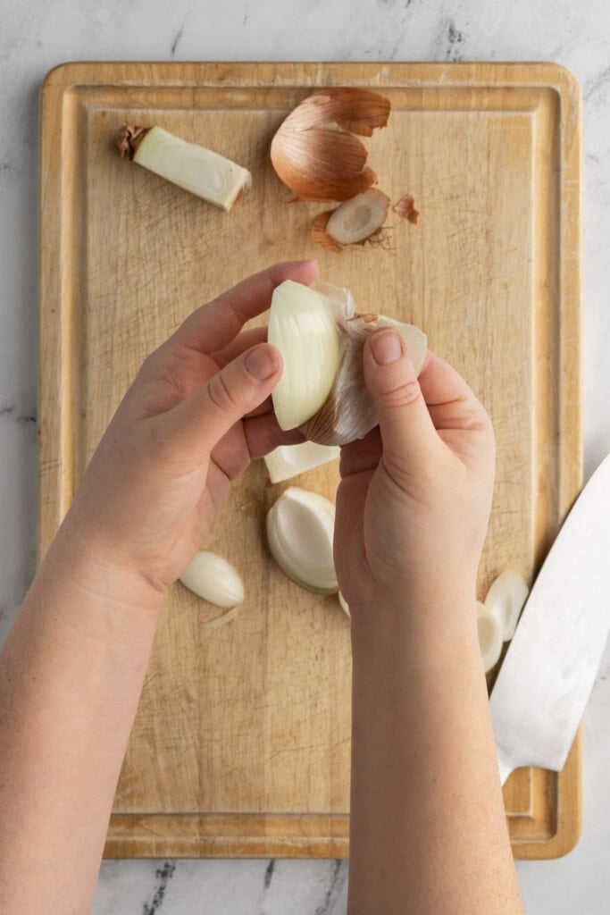 Step three in dicing an onion is peeling off the outer layer