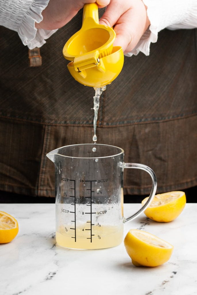 squeezing lemon juice into a measuring cup