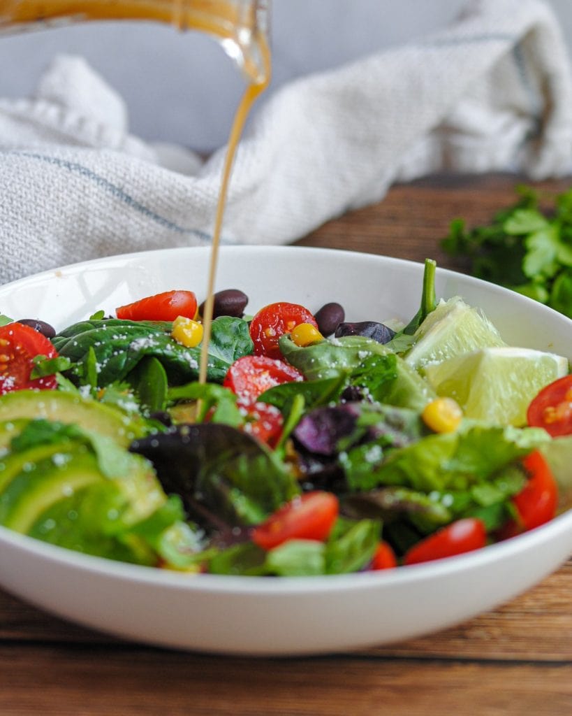 pouring vinaigrette onto a salad