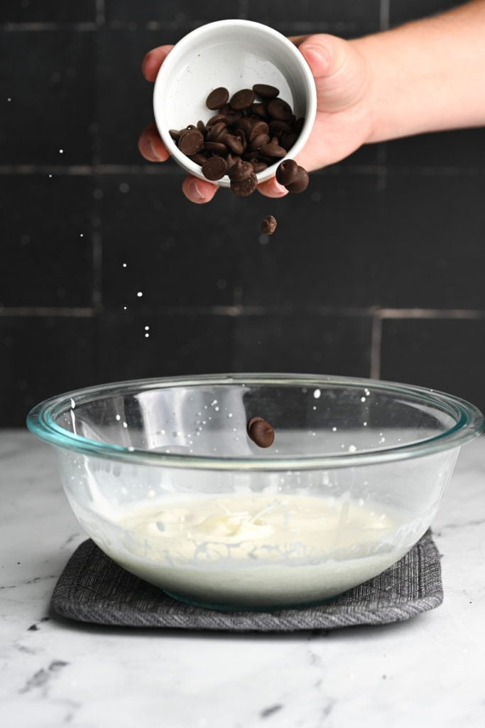 Adding chocolate chips to hot heavy cream to melt