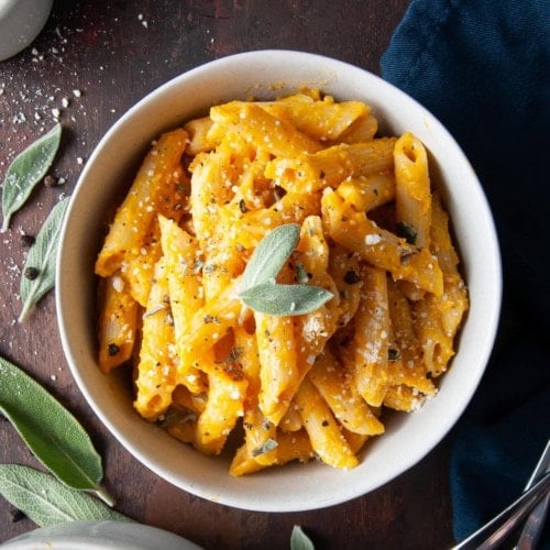 bowl of penne pasta with pumpkin sauce and sage on top