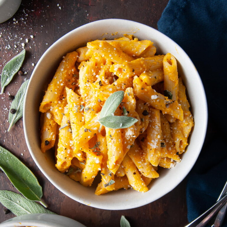 bowl of penne pasta with pumpkin sauce and sage on top