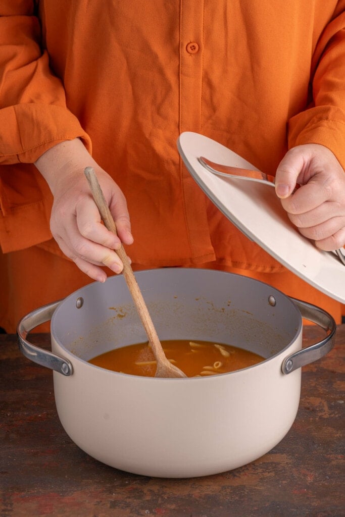 Stirring one pot pasta with pumpkin sauce as it cooks to avoid sticking.