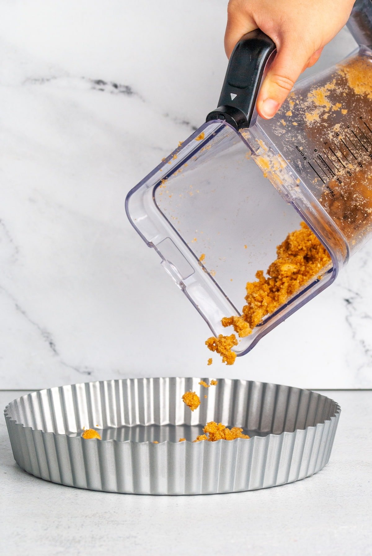 pouring contents of graham cracker crust into pie dish