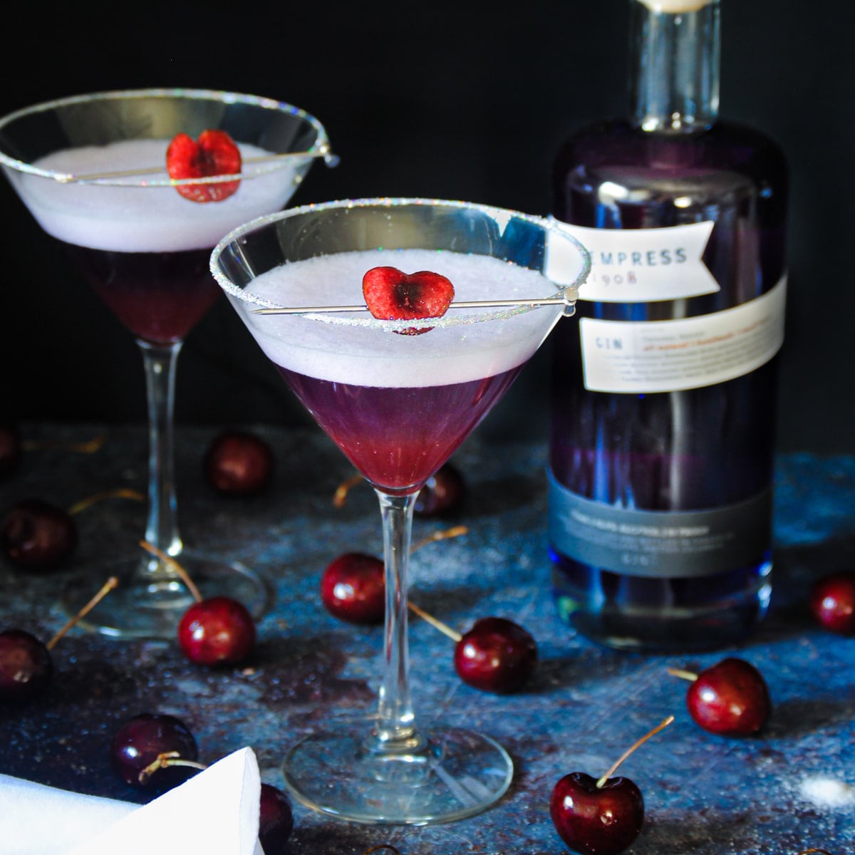 Two Cherry Martinis with Cherry Heart Garnish Two Cherry Martinis made with gin, vermouth, fresh cherry juice, and sugar.
