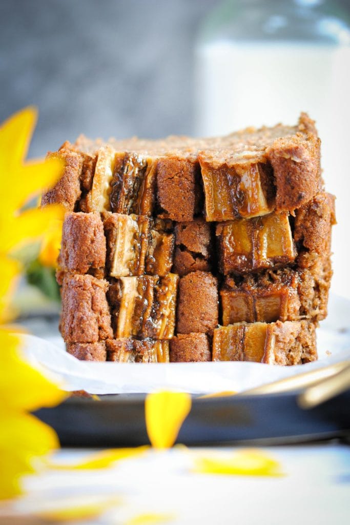 Slices of Vegan Blender Banana Bread stacked on top of each other with a sunflower