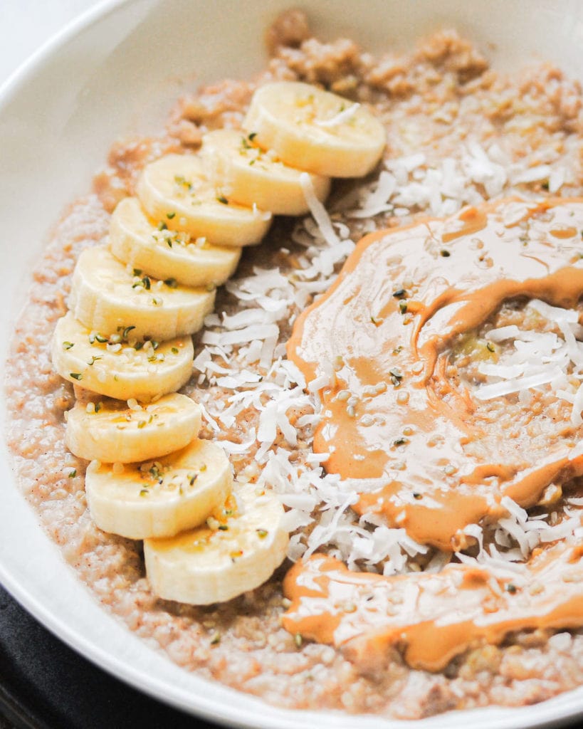 close up of porridge with sliced banana,  peanut butter and coconut flakes