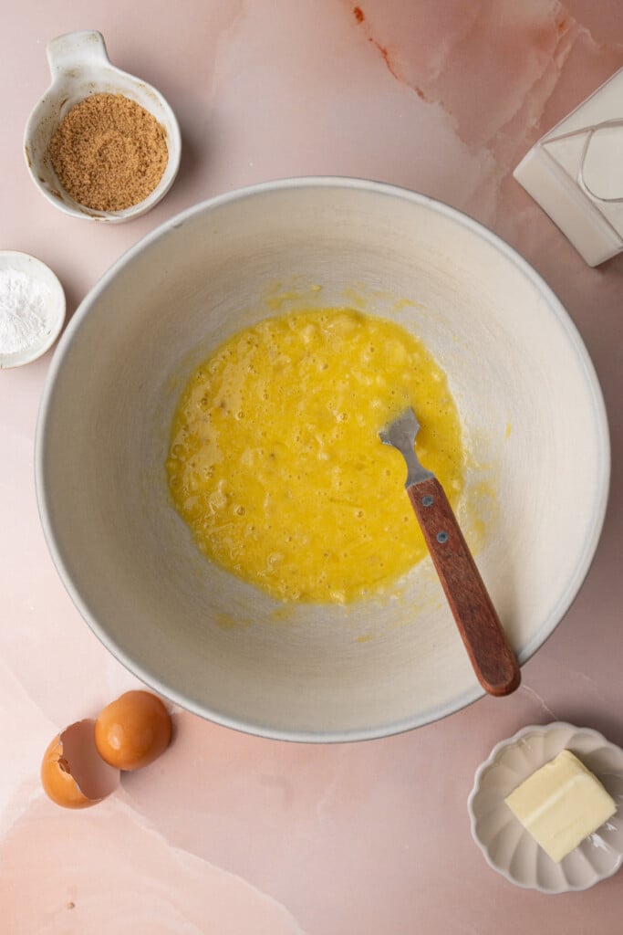 mashed banana and eggs mixed together in a large mixing bowl. 
