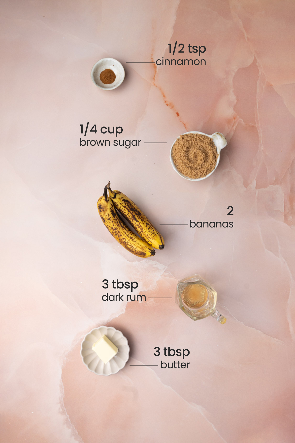 Overhead view of all the ingredients for the topping of Bananas Foster Pancakes - cinnamon, brown sugar, bananas, dark rum, and butter.