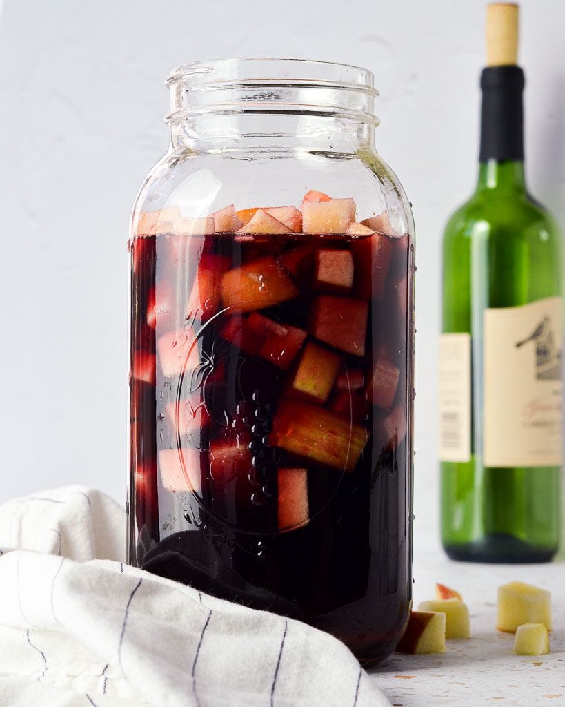 Large mason jar filled with red wine and fruit