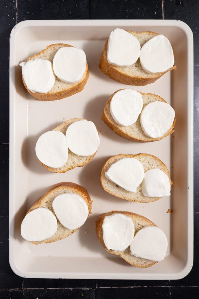 adding fresh mozzarella onto sliced french baguette