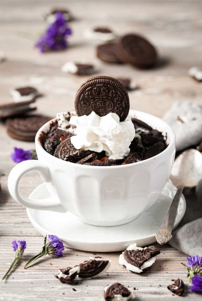 portrait of chocolate mug cake with whipped cream and oreo on top