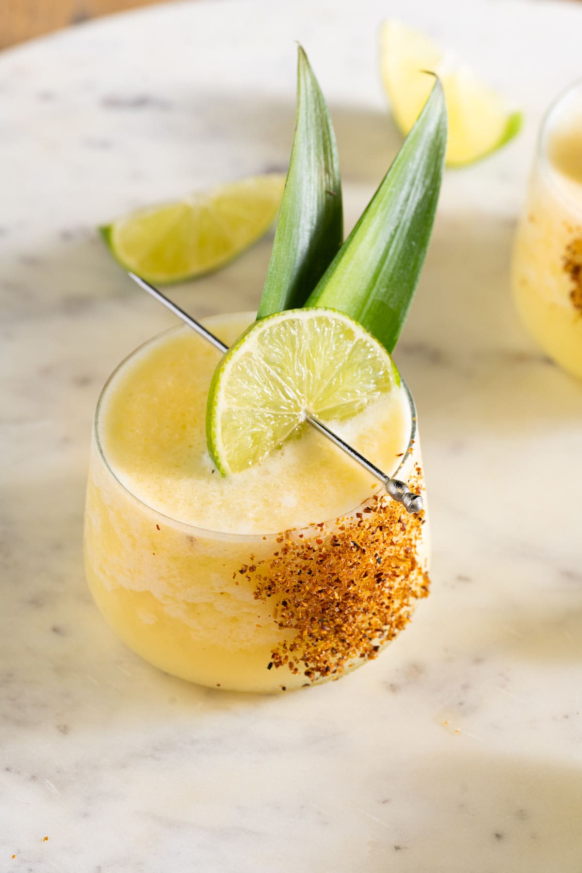 Frozen Pineapple Coconut Margarita in a lowball glass garnished with Tajin