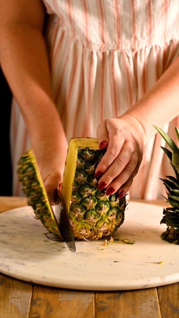 Slicing rind off of whole pineapple