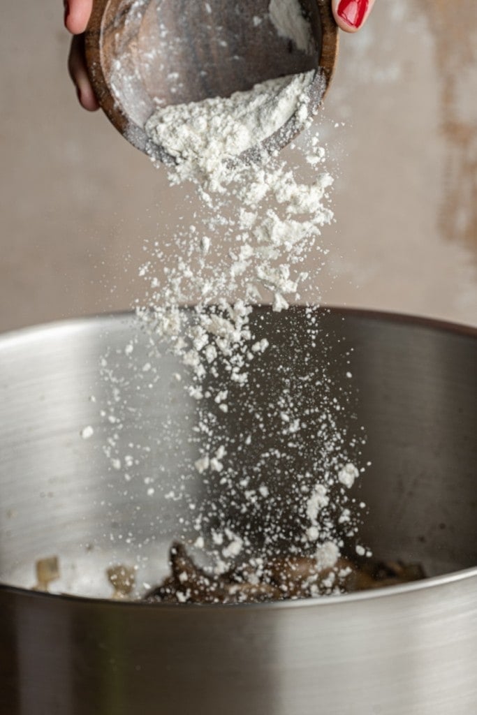 adding flour to a large pot with mushrooms, onions, and butter