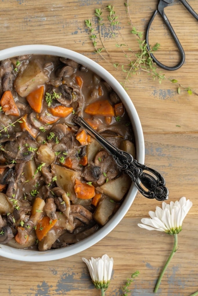 close up of mushroom stew with potatoes and carrots, garnished with fresh thyme 