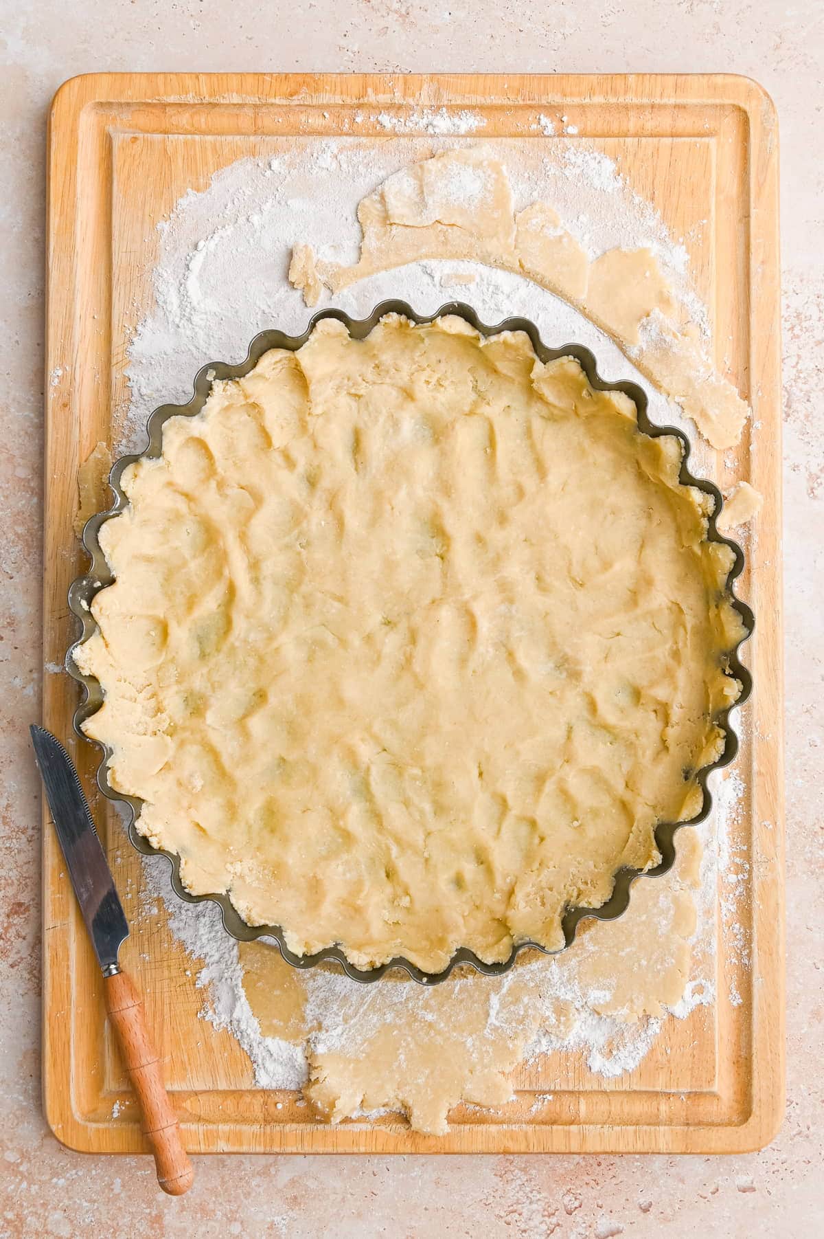 Pushing bottom crust into pie dish before adding peach and mango filling. 