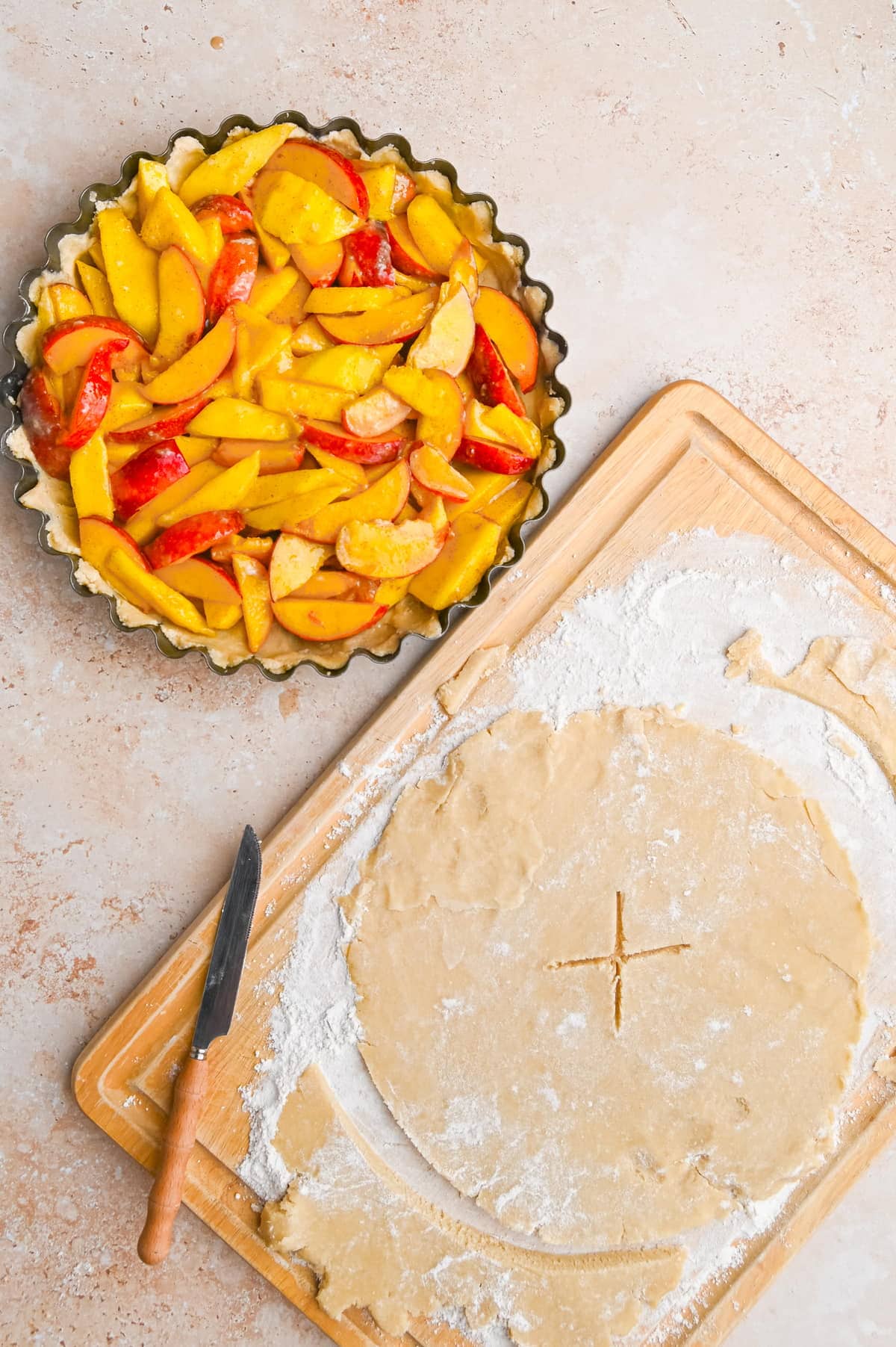 top crust of pie sitting next to pie filled with peaches and mangos ready to be covered