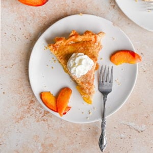 slice of peach mango pie on a plate with three slices of fresh peach and a fork
