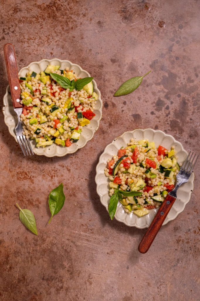 Two plates of Couscous Salad with fresh lemon and basil