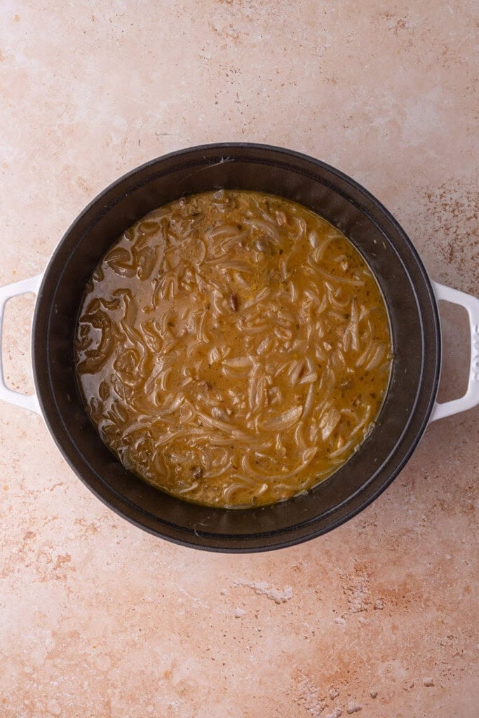 Vegetarian French Onion Soup cooked in a cocotte before serving and adding bread and cheese.