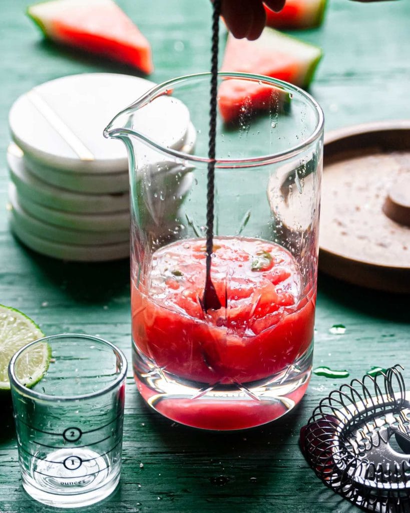 using cocktail spoon to mix watermelon basil margarita