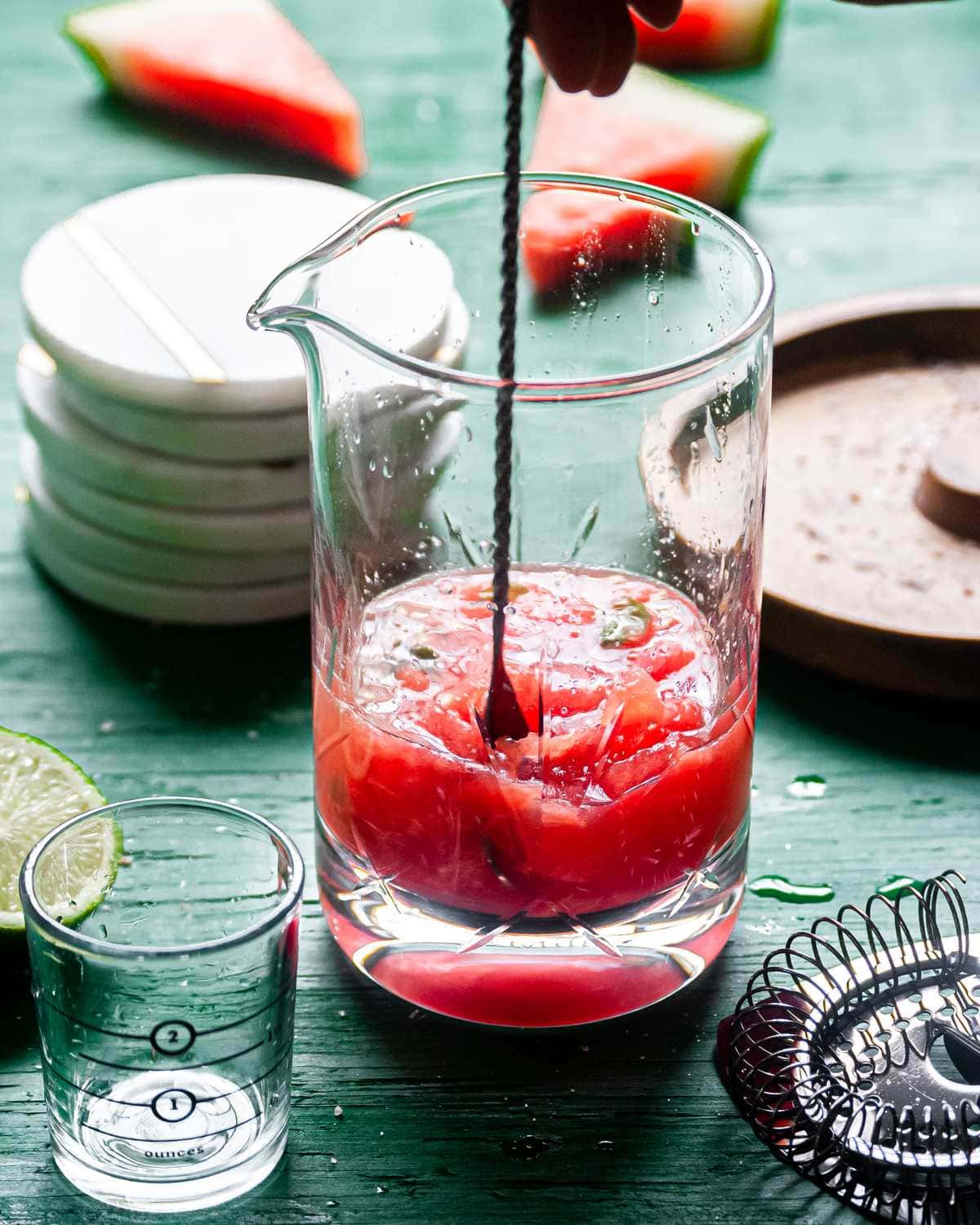 Using cocktail spoon to mix watermelon basil margarita.