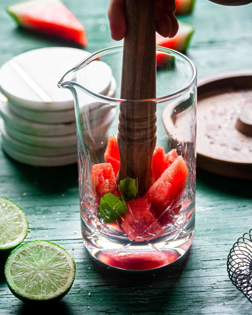 muddling watermelon and fresh basil in mixing glass