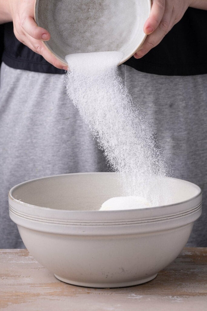 Adding the sugar and softened cream cheese to large bowl to beat together. 