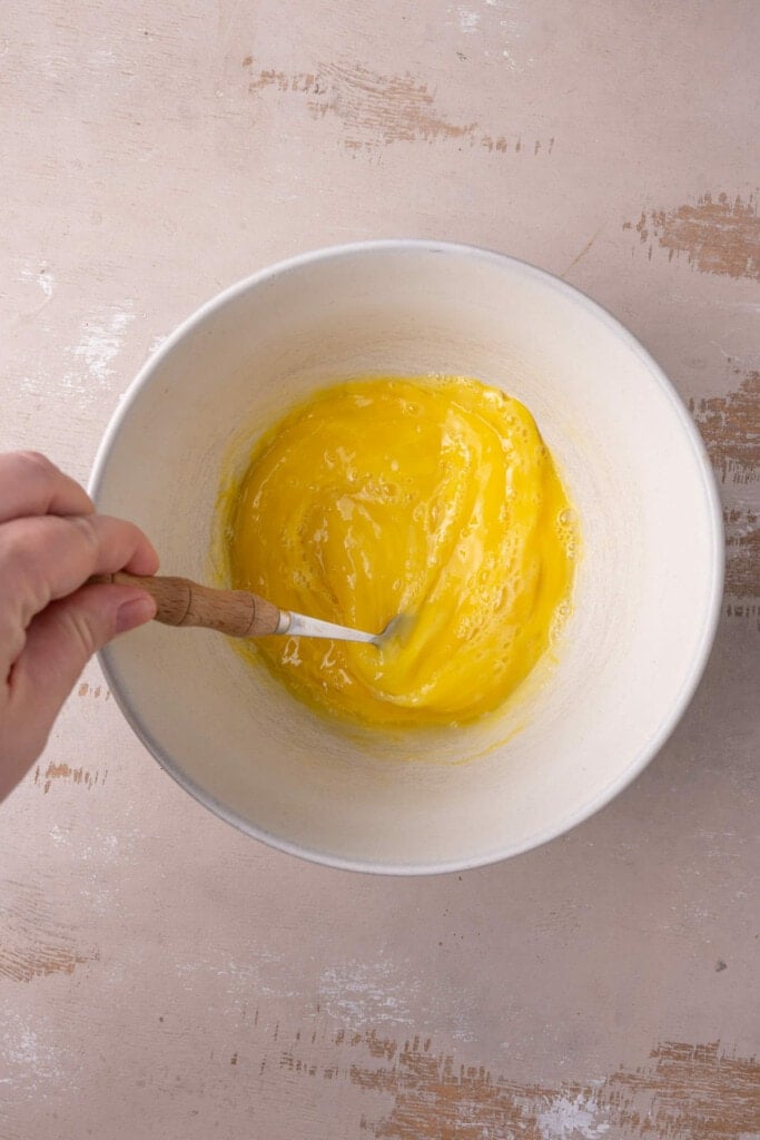 Beating four eggs in a small bowl to combine the whites and yolks. 