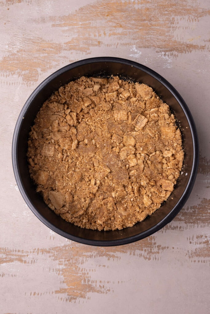 Cinnamon toast crunch-based cheesecake crust in a springform pan. 