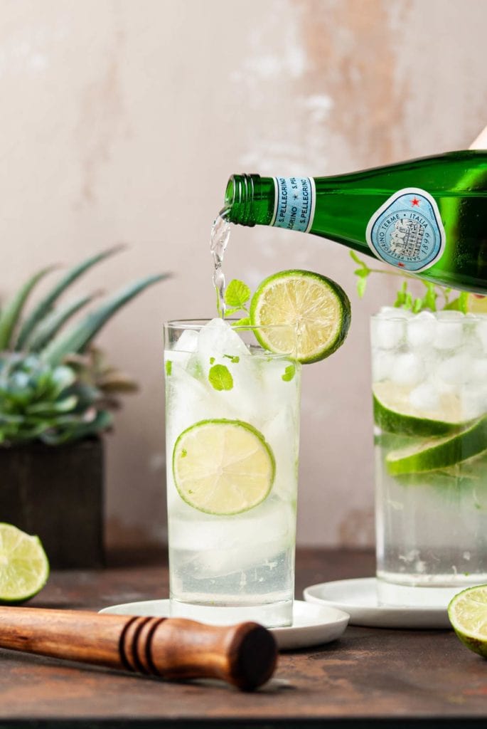 Pouring Sparkling Water into Lime and Mint Cocktail