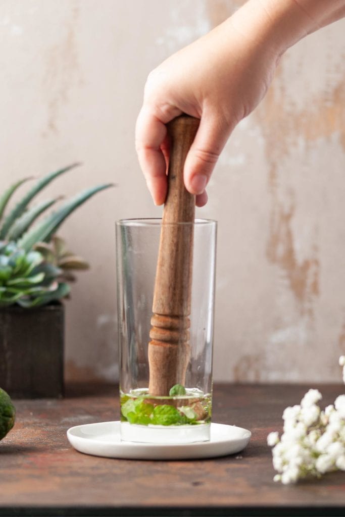 Muddling Mint and Simple Syrup in Highball Glass
