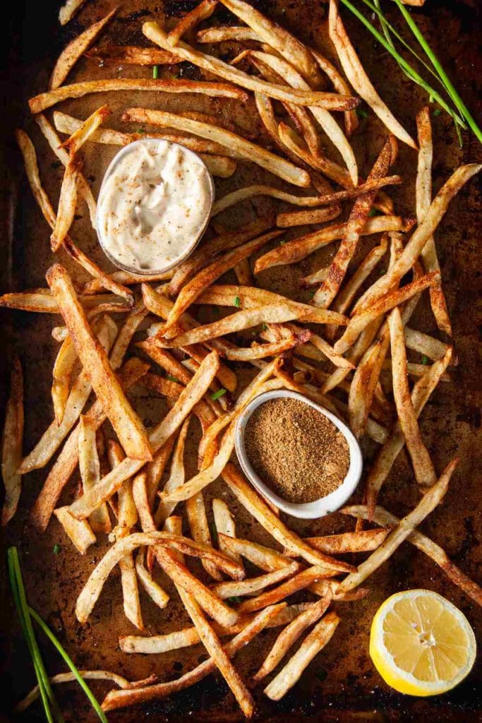 baked golden brown fries on baking sheet with old bay seasoning and old bay aioli