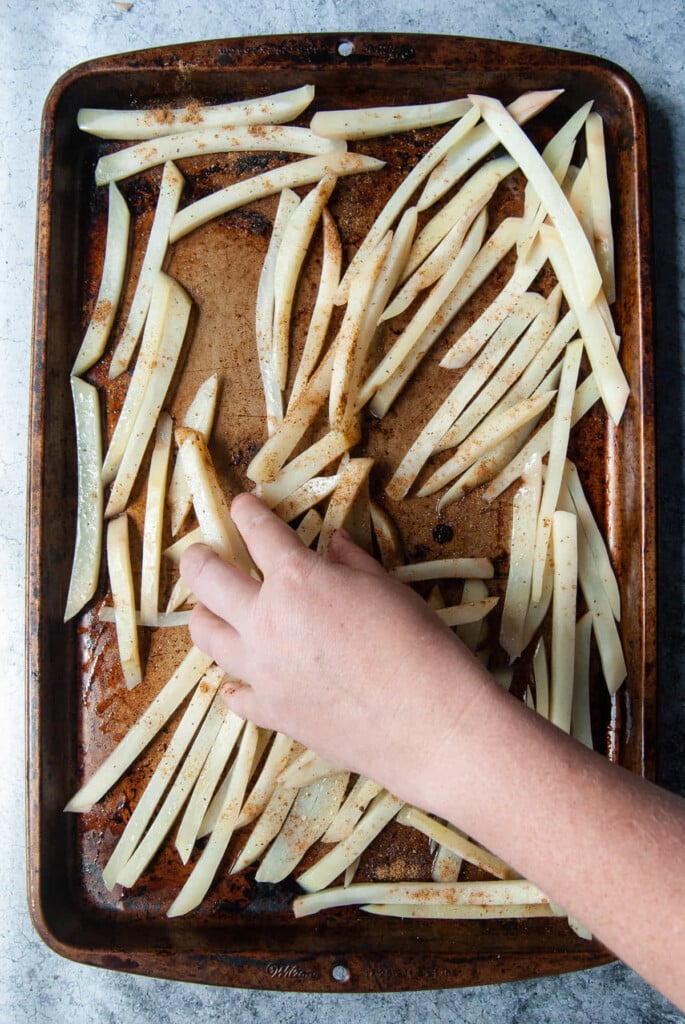 Tossing raw fries with olive oil and Old Bay seasoning.