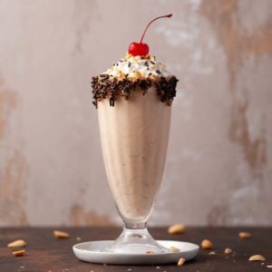 a profile picture of a peanut butter milkshake with whipped cream and a cherry on top