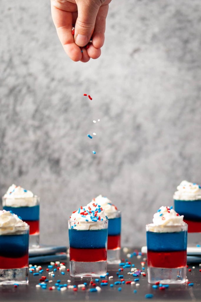 adding patriotic sprinkles on top of whipped cream on jello shots