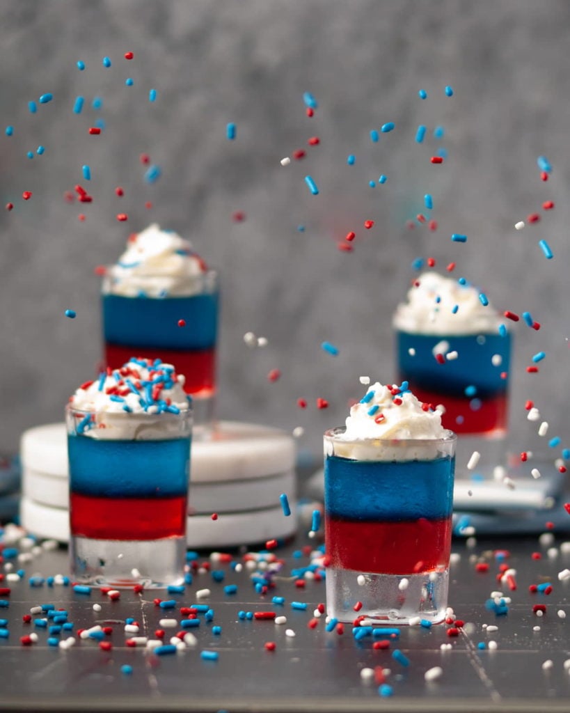 Red White and Blue Jello Shots with Sprinkles Flying in the Air