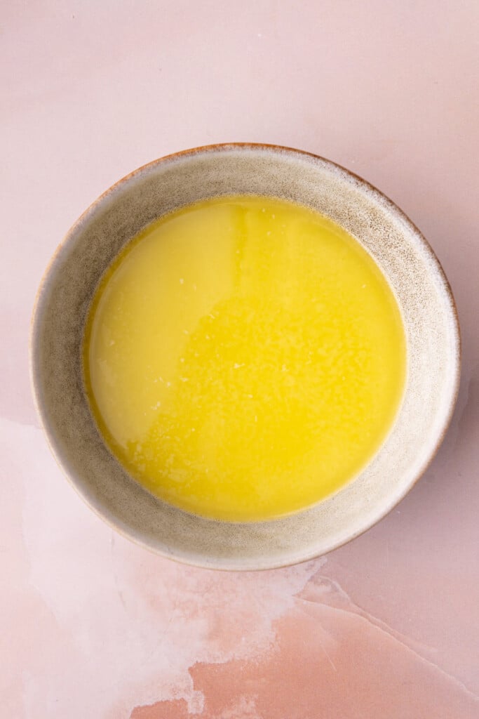 Melted butter in a bowl to use in a savory breakfast casserole. 