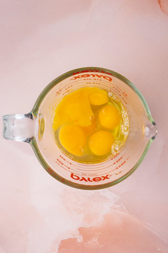 Six eggs cracked in a measuring cup. 