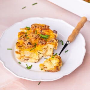 Thick slice of savory breakfast casserole on a white plate with a forkful off to the side.