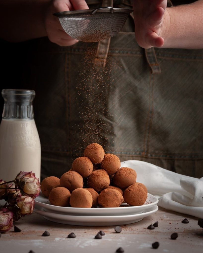 cocoa powder falling on to stacked chocolate truffles