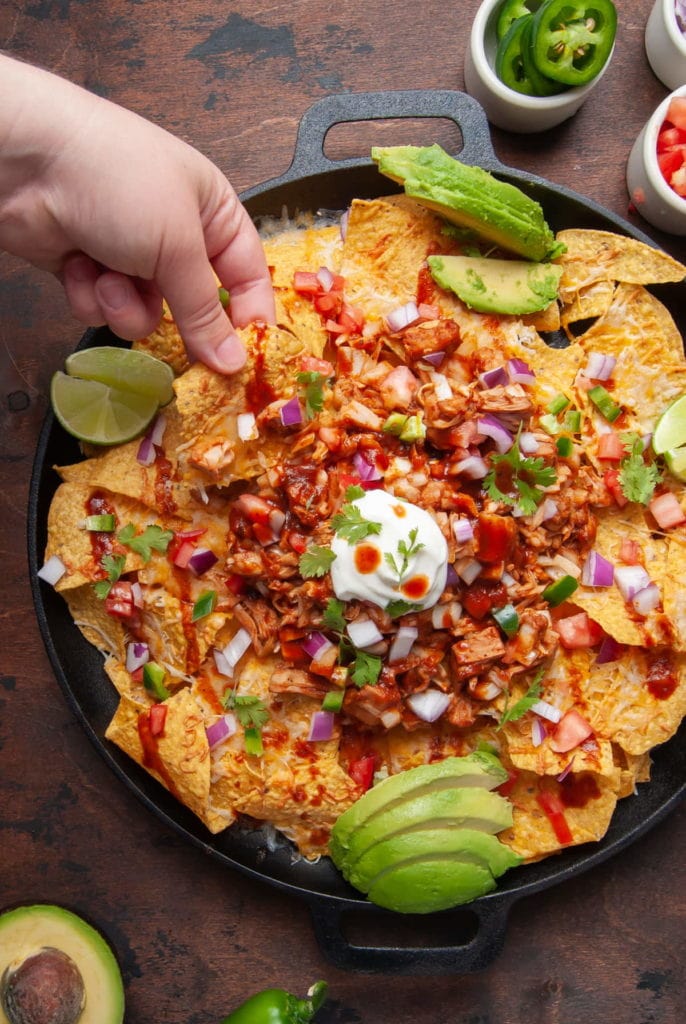 hand reaching in to grab nachos