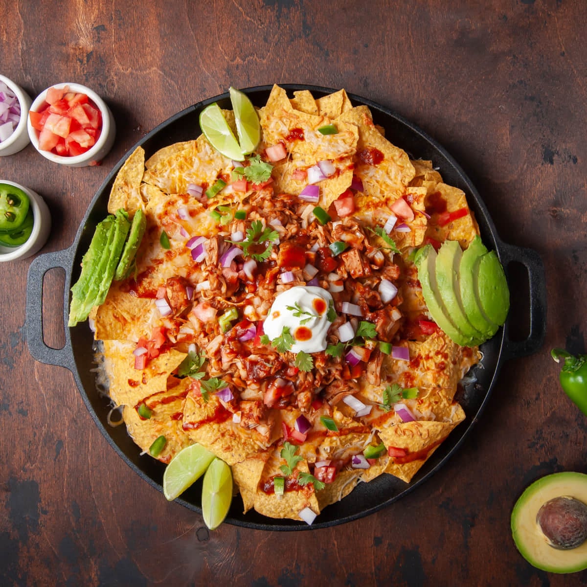 Overhead image of BBQ Jackfruit Nachos with sour cream, avocado and lime.
