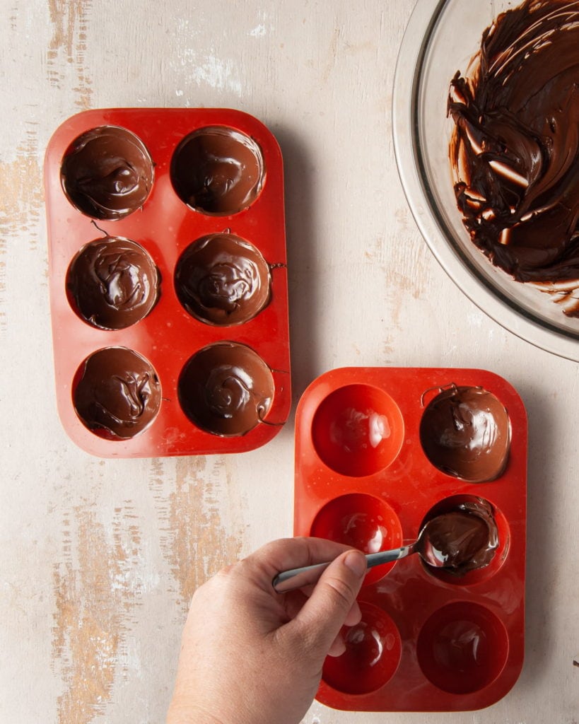 filling spherical chocolate molds with tempered chocolate