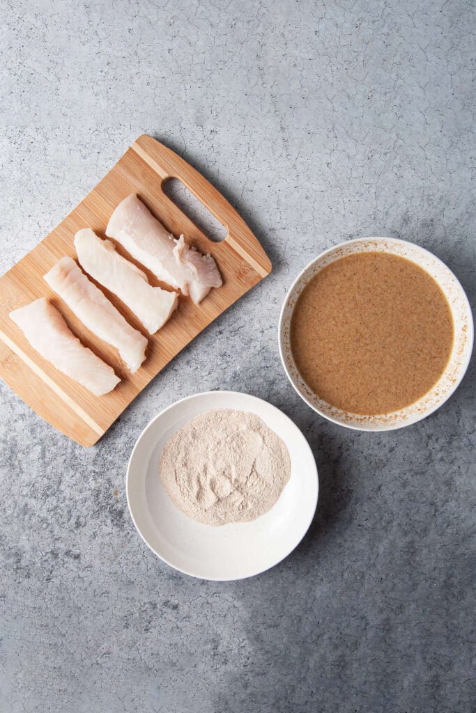 Assembly line for coating halibut in flour and batter.